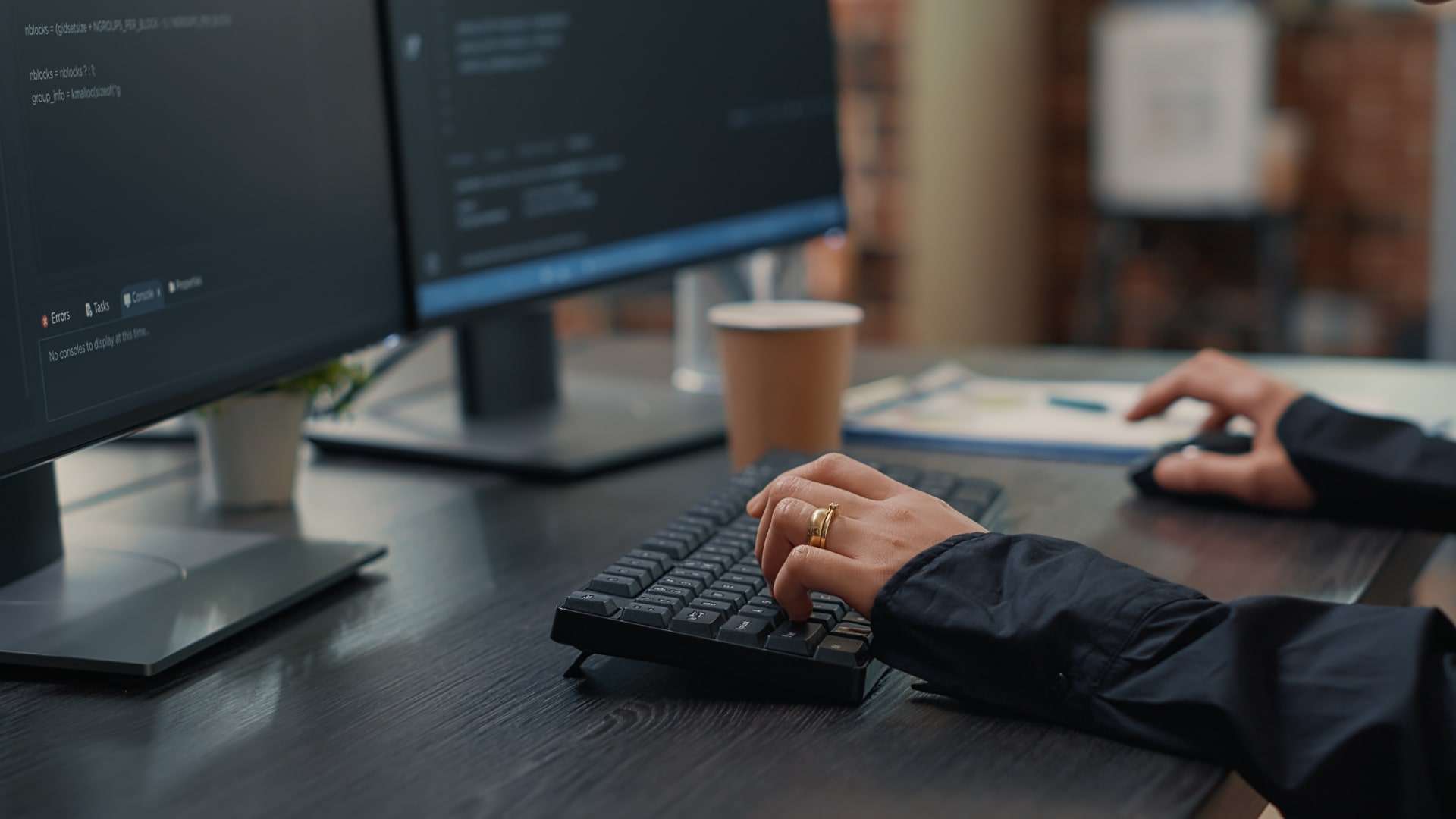 Closeup of developer hands typing code on keyboard while looking at computer screens with programming interface. software programmer sitting at desk with clipboard writing algorithm.