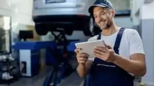 Happy auto repairman working on touchpad in a workshop