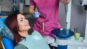 A young redhead woman having examination while sitting in a dental chair in the clinic.