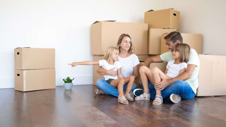 Familia feliz sentada en el piso en casa nueva cerca de cajas de cartón